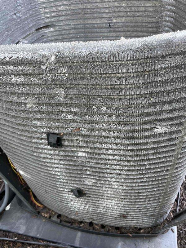 Completed comprehensive BFMA tune-up on 3-year-old residential air conditioning system. Upon arrival, discovered significant frost accumulation on condenser coil indicating potential refrigerant charge issue or restricted airflow. Inspected outdoor unit positioned on concrete pad with adequate clearance, noting debris and organic matter lodged between coil fins. Performed standard maintenance protocol including coil cleaning to remove accumulated dust, leaves, and debris from aluminum fins to restore proper heat exchange efficiency. Evaluated system operation, checked refrigerant levels, and addressed frost condition to ensure optimal cooling performance and prevent compressor damage.