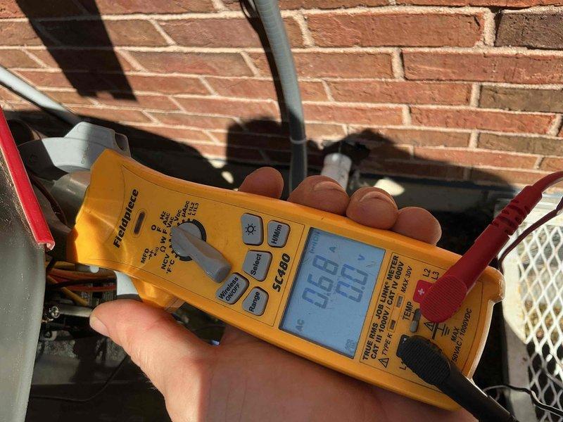 Completed comprehensive BFMA tune-up on residential air conditioning system over 4 years old. Performed electrical diagnostics using multimeter to verify proper voltage and amperage readings at outdoor unit. Inspected capacitor showing model 01SC139RC0 rated at 21ufd 370V, noting white residue buildup on equipment surface and mounting platform indicating possible condensation or corrosion concerns that were addressed during service.