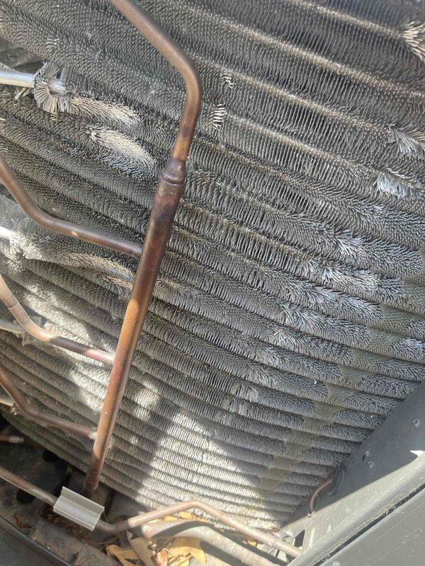 Completed comprehensive BFMA tune-up on 7-year-old air conditioning system. Inspected outdoor condenser unit, including heat exchanger coils, refrigerant lines, and electrical components. Documented accumulation of debris and organic material in coil assembly and noted copper refrigerant tubing connections showing normal patina consistent with unit age.