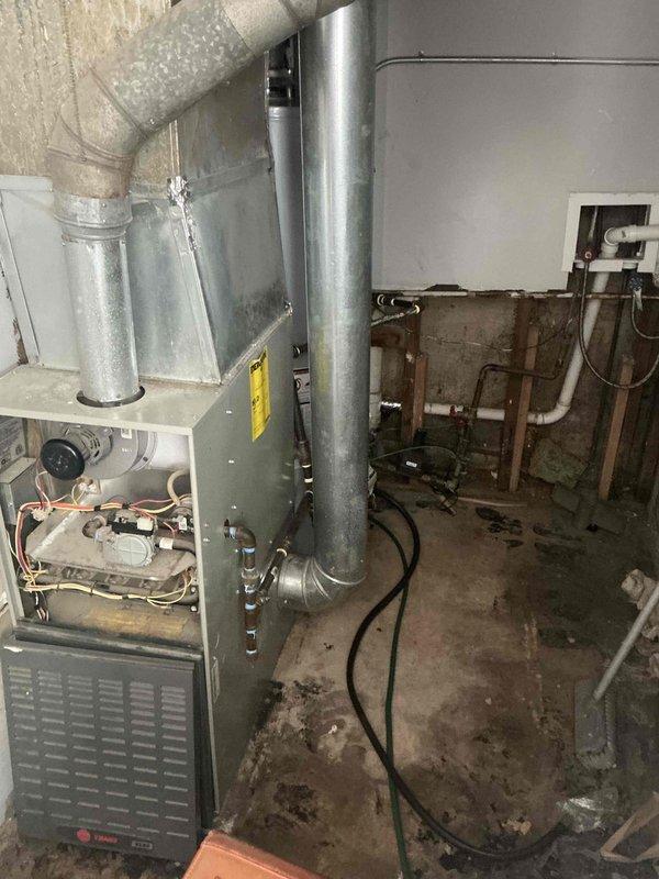 Conducted sales estimate for furnace replacement in basement location where existing Trane unit sustained flood damage and is non-operational. Assessed current HVAC system including older air conditioning equipment and documented existing ductwork configuration with metal supply and return runs. Discussed full system replacement benefits given the age of the AC unit and immediate need for heating restoration, with customer requesting expedited timeline for installation.
