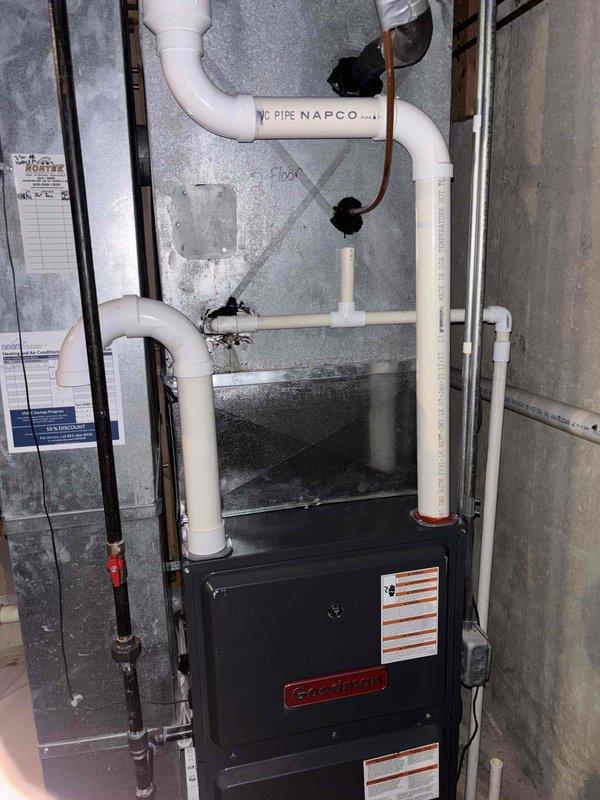 Responded to no cooling call regarding reported refrigerant leak on residential Goodman furnace system. Upon arrival, performed visual inspection of indoor unit and associated components including condensate drainage system, PVC vent piping, and refrigerant lines. Documented equipment installation with photographs showing furnace, white PVC condensate and vent pipes, copper refrigerant lines, and electrical connections. System assessed for visible signs of refrigerant leakage, condensate issues, and proper venting. Unit operational at time of inspection with no immediate leaks detected during visual examination.