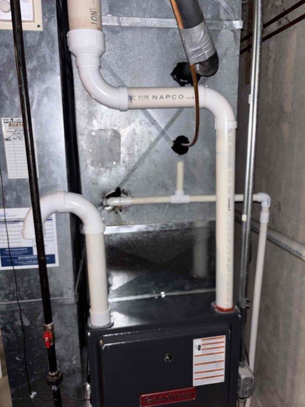 Responded to no cooling call regarding reported refrigerant leak on residential Goodman furnace system. Upon arrival, performed visual inspection of indoor unit and associated components including condensate drainage system, PVC vent piping, and refrigerant lines. Documented equipment installation with photographs showing furnace, white PVC condensate and vent pipes, copper refrigerant lines, and electrical connections. System assessed for visible signs of refrigerant leakage, condensate issues, and proper venting. Unit operational at time of inspection with no immediate leaks detected during visual examination.