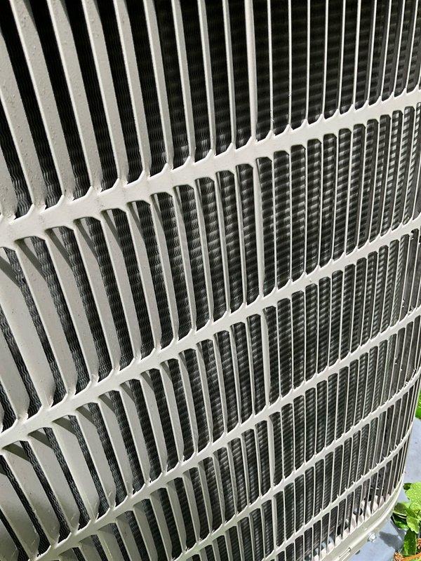 Completed comprehensive BFMA tune-up service on a 4+ year old outdoor air conditioning condenser unit located against the exterior brick wall. Performed standard maintenance procedures including inspection of the condenser coils, protective grille, and louver system, all of which were found to be in clean and well-maintained condition with no visible debris accumulation, rust, or damage. Unit is operating properly with adequate airflow through the horizontal fin assembly and protective components.