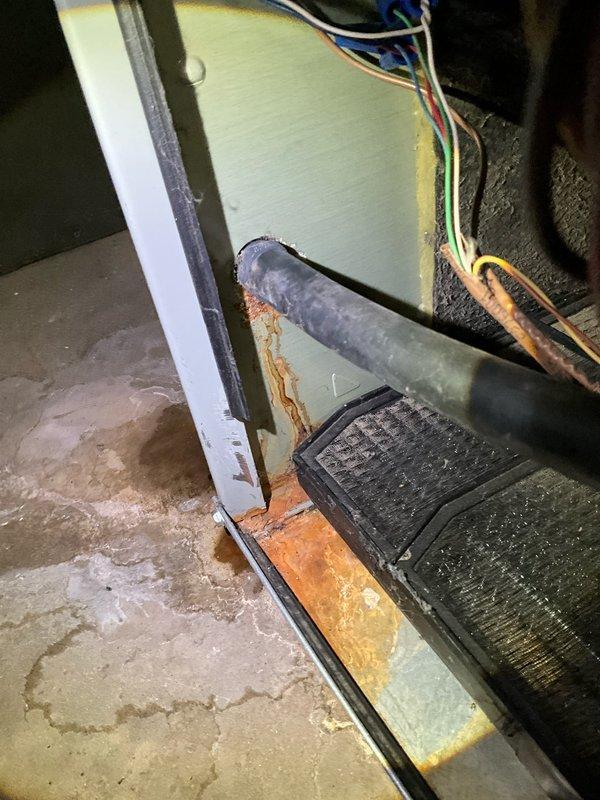 Completed comprehensive annual air conditioning maintenance at residential property. Performed full system inspection of outdoor condenser unit and indoor air handler components. Observed significant rust staining on concrete floor near air handler base and around PVC condensate drain line, indicating potential moisture concerns. Exterior condenser coils showed moderate accumulation of dirt, debris, and weathering with visible discoloration. Cleaned condenser coils, checked refrigerant levels, inspected electrical connections and wiring, verified proper drainage function, and tested system operation. Recommended monitoring condensate drain area for continued moisture issues and potential future maintenance of drain pan integrity.