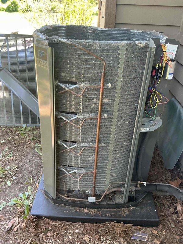 Completed comprehensive BFMA tune-up on outdoor air conditioning condenser unit. Removed protective grille to access internal coil assembly, performed thorough inspection of evaporator coils showing age-related weathering and darkening of fins. Connected refrigerant gauges to service ports and verified system pressures, recording readings of 996 PSI and 02 on digital multimeter. Tested electrical components including GE capacitor using Fieldpiece SC440 meter to ensure proper voltage and amperage levels. Inspected copper refrigerant lines and connections for leaks or damage, cleared debris from unit base and surrounding area, and reassembled unit upon completion of all diagnostic and maintenance procedures.