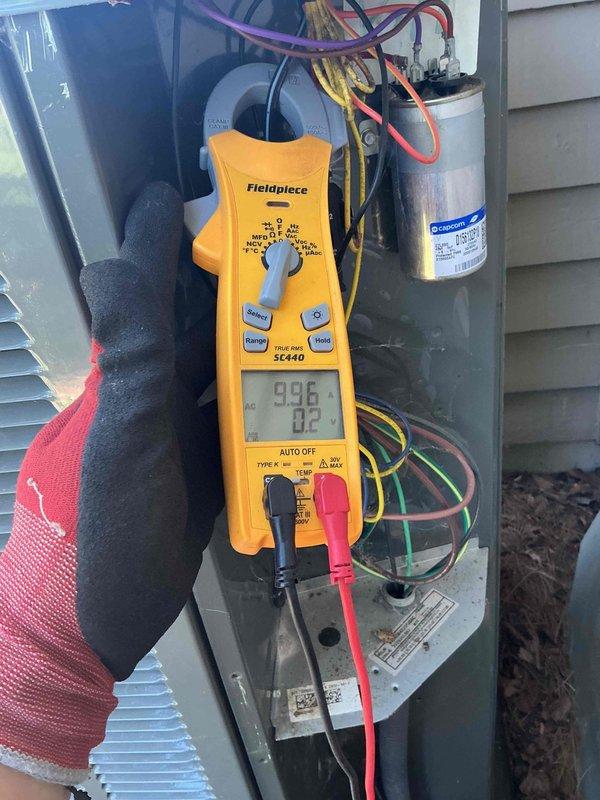 Completed comprehensive BFMA tune-up on outdoor air conditioning condenser unit. Removed protective grille to access internal coil assembly, performed thorough inspection of evaporator coils showing age-related weathering and darkening of fins. Connected refrigerant gauges to service ports and verified system pressures, recording readings of 996 PSI and 02 on digital multimeter. Tested electrical components including GE capacitor using Fieldpiece SC440 meter to ensure proper voltage and amperage levels. Inspected copper refrigerant lines and connections for leaks or damage, cleared debris from unit base and surrounding area, and reassembled unit upon completion of all diagnostic and maintenance procedures.