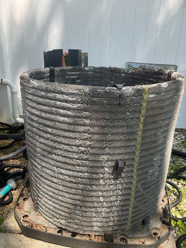 # HVAC Maintenance - BFMA Tune Up Completed

Performed comprehensive BFMA tune-up service on 14+ year old residential air conditioning system during afternoon service window. Upon arrival, conducted thorough visual inspection of outdoor condenser unit, which revealed significant deterioration of protective coil wrap with multiple tears, gaps, and heavy soiling from prolonged environmental exposure. Base plate exhibited moderate rust and corrosion at mounting points and edges, consistent with age of equipment.

Inspected condenser coil assembly and identified substantial accumulation of dirt, dust, and debris throughout fin surfaces, creating restricted airflow conditions. Coil fins displayed typical oxidation and contamination buildup in horizontal striped pattern across heat exchange surfaces. Verified refrigerant line connections and observed normal oxidation on copper piping consistent with outdoor installation age.

Examined electrical components including capacitor and control box