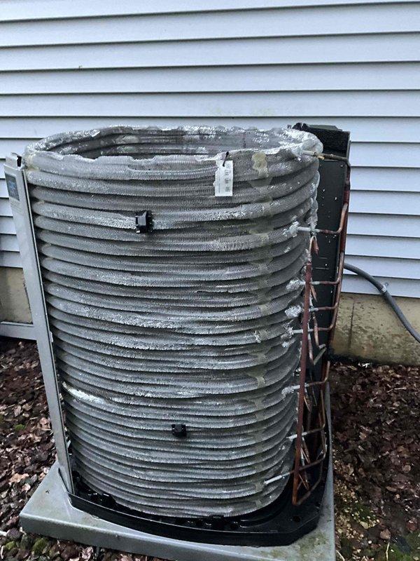 Completed comprehensive BFMA tune-up on 3-year-old residential air conditioning system during late afternoon service call. Upon arrival, performed standard maintenance inspection of outdoor condenser unit, removed protective casing to access internal components, and discovered significant frost and ice accumulation on cylindrical condenser coil assembly indicating potential refrigeration cycle issues or improper system operation. Documented unit condition with photographic evidence showing extensive crystalline frost buildup obscuring metal fins and coil surfaces, cleaned and serviced accessible components, verified unit positioning on concrete pad with proper clearances from vinyl siding, and ensured system readiness for continued operation.
