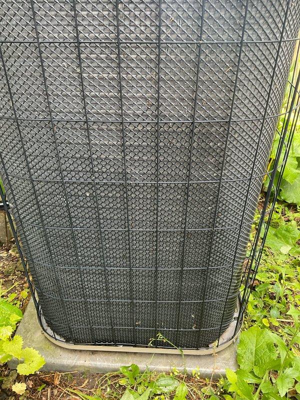Completed comprehensive BFMA tune-up service on 20-year-old outdoor air conditioning condenser unit. Performed standard maintenance protocol including system inspection, component testing, and operational verification. Unit was accessed despite significant vegetation overgrowth around the base and perimeter; condenser found in operational condition with protective mesh covering intact and properly secured to wire grid framework.