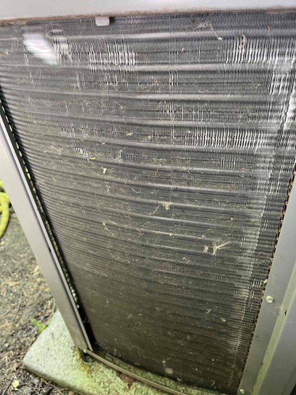 Completed comprehensive BFMA tune-up service on an 8-year-old Armstrong Air condensing unit and water heater system. Performed thorough inspection of outdoor condenser unit, which exhibited significant dirt and debris accumulation on coil fins and heat exchanger surfaces, particularly in middle and lower sections. Cleaned condenser coils to restore proper airflow and heat transfer efficiency, removing caked-on dust, dirt, and organic debris that had accumulated between fins. Inspected fan motor assembly, electrical connections, and refrigerant lines running along exterior wall. Verified proper operation of condenser fan and checked top-mounted fan guard for secure installation. Assessed unit's exterior condition, noting weathering consistent with outdoor exposure on concrete pad. Performed standard maintenance procedures on water heater system per BFMA protocol. All equipment operational upon completion of tune-up service.