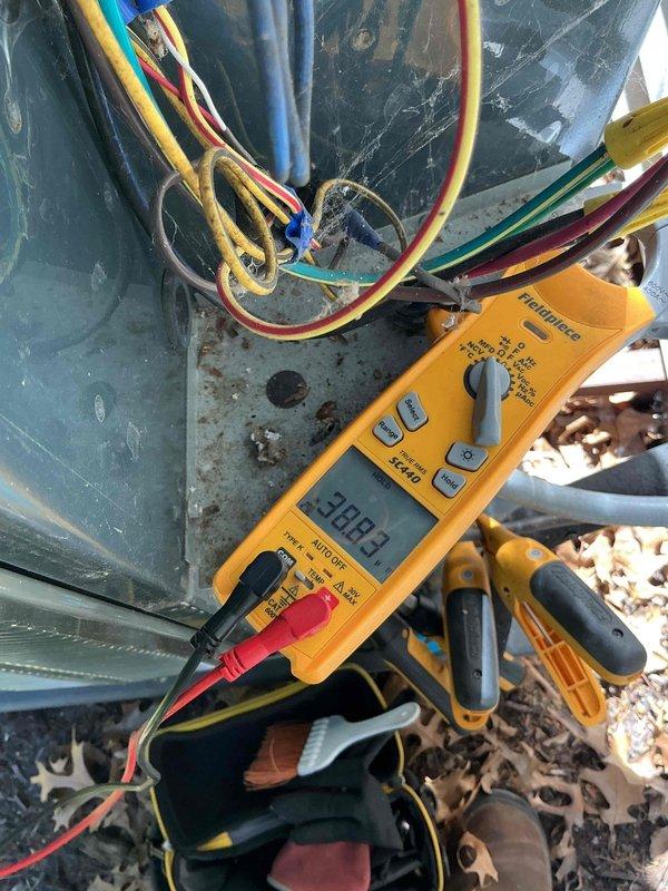 Completed comprehensive BFMA tune-up service on residential air conditioning system aged 6+ years during afternoon appointment window. Performed diagnostic testing with digital multimeter, recording voltage reading of 308.4V at outdoor unit terminal connections, verified proper electrical connections across line voltage and low voltage wiring including yellow, red, white, blue, and ground conductors. Inspected cylindrical outdoor heat pump unit with corrugated metallic housing, confirmed unit operational status, and documented equipment condition showing age-appropriate exterior wear on metal surfaces.