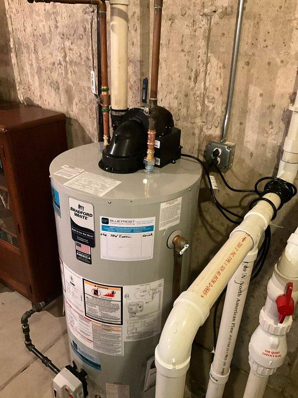 Removed existing water heater from basement utility area and properly disposed of old unit. Installed new 50-gallon natural gas Bradford White power vent water heater with 6-year tank warranty and 1-year parts and labor warranty. Modified and connected gas supply line with appropriate fittings to ensure proper fuel delivery. Reconfigured water supply and discharge lines using copper piping with brass fittings for hot and cold water connections. Installed power vent system with black exhaust component mounted on top of unit and routed flue piping according to manufacturer specifications. Made necessary modifications to existing PVC drainage system with red-handled valve for proper condensate management. Connected electrical supply with appropriate cord and power connection for power vent operation. Verified all connections for leaks, tested gas pressure, confirmed proper venting operation, and ensured unit fired correctly. Left installation area clean with all plumbing, gas, and electri