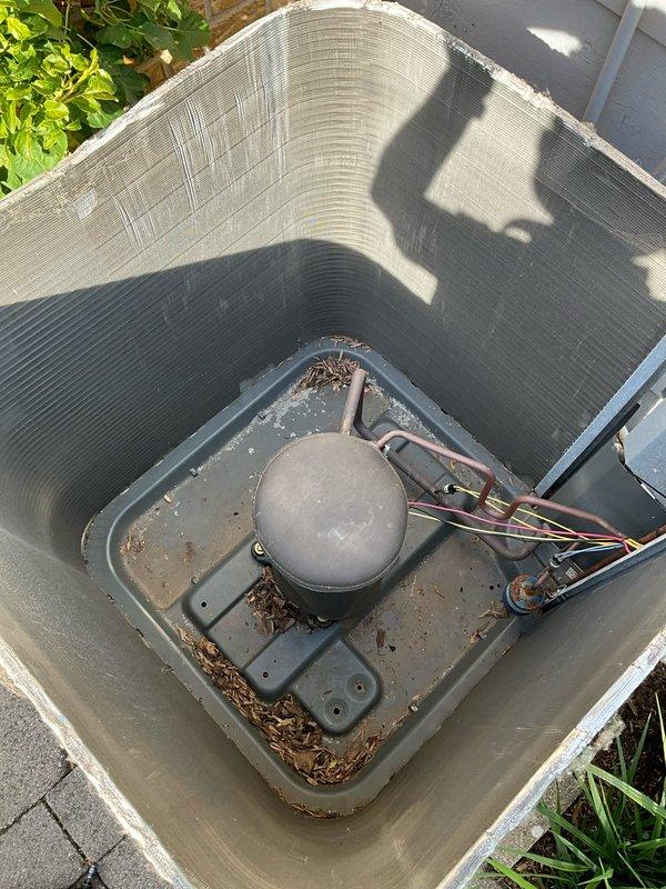 Completed comprehensive BFMA tune-up on 10+ year old air conditioning system during afternoon appointment window. Performed standard maintenance protocol including inspection of thermostat operation (currently set to cool to 62°F with actual indoor temperature at 73°F), verified system controls and WiFi connectivity functioning properly. Inspected outdoor condenser unit, noted accumulation of leaves, twigs, and debris in base pan around compressor; cleared debris from unit interior and verified all electrical connections and wiring harness secure. System operational upon completion of tune-up service.