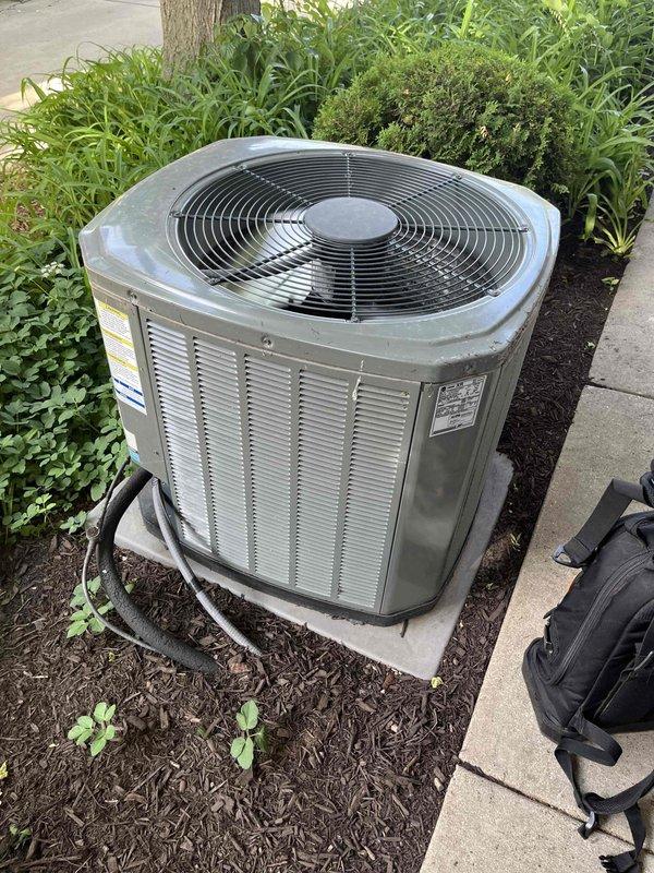 Completed BFMA preventive maintenance tune-up on outdoor air conditioning condenser unit. Performed comprehensive system inspection, cleaned condenser coils and removed accumulated organic debris including leaves and plant growth from base pan area. Inspected refrigerant lines, electrical connections, and fan assembly; verified proper airflow through louvers and grille. Unit operating within normal parameters upon completion of service.