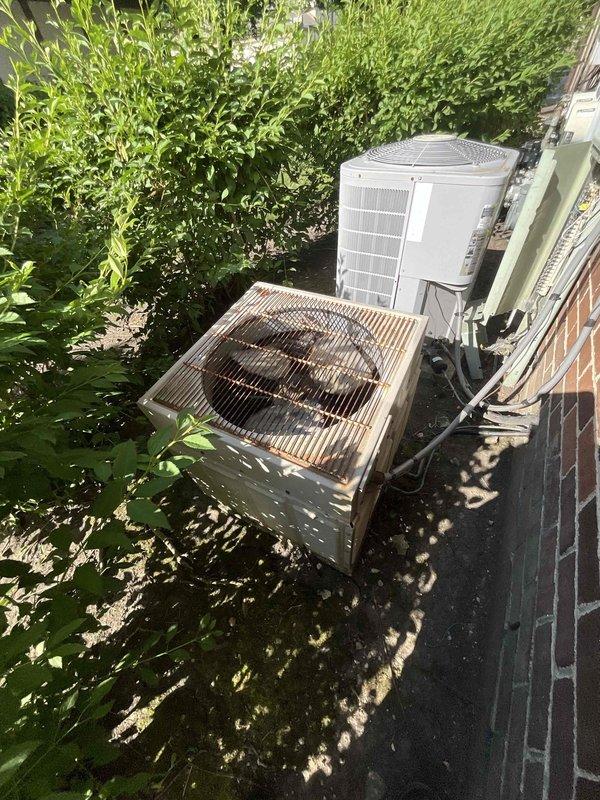 Completed comprehensive air conditioning tune-up maintenance on residential cooling system during afternoon service call. Performed standard preventive maintenance procedures including inspection of outdoor condensing unit, verification of refrigerant levels, electrical component testing, and system operational checks. Documentation photos captured equipment condition showing older outdoor unit with visible corrosion and rust on protective grille, along with indoor water heater and associated plumbing connections for reference.