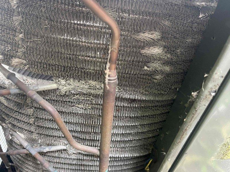Responded to service call for non-operational air conditioning system and performed comprehensive BFMA tune-up on Trane XR condensing unit. Conducted thorough inspection of 4+ year old equipment, identifying significant debris accumulation and fibrous material buildup within condenser coils that was restricting airflow and reducing system efficiency. Cleaned heat exchanger coils to restore proper heat transfer capability, inspected copper refrigerant lines showing surface oxidation but maintaining structural integrity, verified fan operation and electrical connections, and tested system performance. Unit restored to proper working condition with improved airflow through coil assembly, ensuring optimal cooling capacity for continued operation.