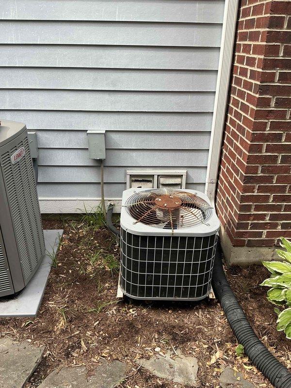 Conducted on-site evaluation of 21-year-old residential HVAC system for replacement estimate. Inspected outdoor condensing unit positioned in narrow side yard between building walls, noting age-appropriate wear on cylindrical white housing and top-mounted fan assembly. Documented refrigerant line routing and electrical connections at exterior installation.

Assessed indoor air handler unit in basement mechanical room, identifying critical operational failure evidenced by extensive frost and ice accumulation on vertical supply ductwork and unit surfaces. This severe icing condition indicates refrigerant system malfunction, likely due to low refrigerant charge, restricted airflow, or failed metering device typical of equipment at end of service life. Verified Carrier brand air handler with connected ductwork and refrigerant lines showing signs of age-related deterioration.

Provided comprehensive replacement estimate for complete HVAC system upgrade based on observed equipment age, curre