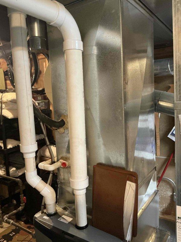 Conducted comprehensive assessment of residential HVAC system including 27-year-old air conditioning unit and 12-year-old furnace. Customer reported AC had recently frozen during operation and was shut down to defrost. Evaluated outdoor condensing unit mounted on platform with refrigerant lines, electrical disconnect, and mounting hardware. Inspected indoor air handler system with PVC condensate drainage and venting components. Documented existing equipment condition and configuration to provide replacement estimate for aging AC system and coil assembly due to advanced age and recent freezing issue indicating potential refrigerant or airflow concerns.