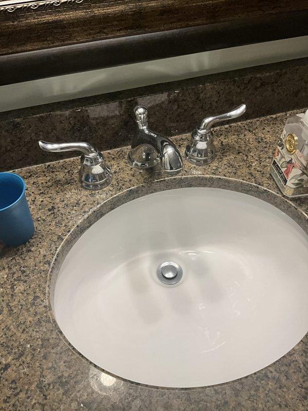 Completed comprehensive plumbing inspection during morning service window. Inspected bathroom vanity plumbing system including chrome three-piece faucet assembly, undermount sink with drain stopper, and supply line connections beneath granite countertop. All fixtures found to be in proper working condition with no visible leaks or drainage issues detected.