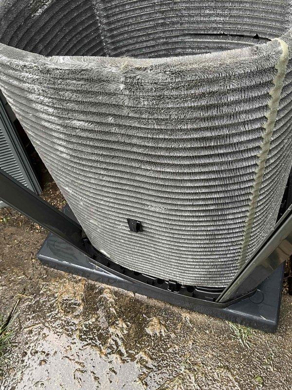 Completed comprehensive BFMA tune-up service on residential air conditioning system aged 4+ years. Performed thorough inspection of outdoor condenser unit, which exhibited heavy accumulation of dust, dirt, and debris throughout the cylindrical coil fins, significantly impacting airflow and heat transfer efficiency. Cleaned condenser coils to remove thick buildup from horizontal fin surfaces, restored proper airflow clearance, and verified refrigerant line connections and electrical conduit integrity. System operational and ready for continued service.