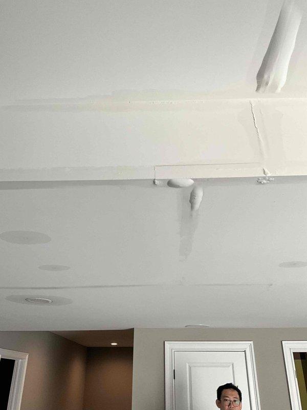 Responded to after hours call for ceiling damage assessment. Upon arrival, documented visible vertical crack where ceiling meets wall near HVAC/plumbing conduit and access panel, indicating possible structural settling. Also identified and photographed ceiling-mounted smoke detector with significant circular water staining and discoloration surrounding the unit, suggesting active or previous moisture intrusion from above. Recommended follow-up inspection to determine water source and assess extent of damage requiring repair.