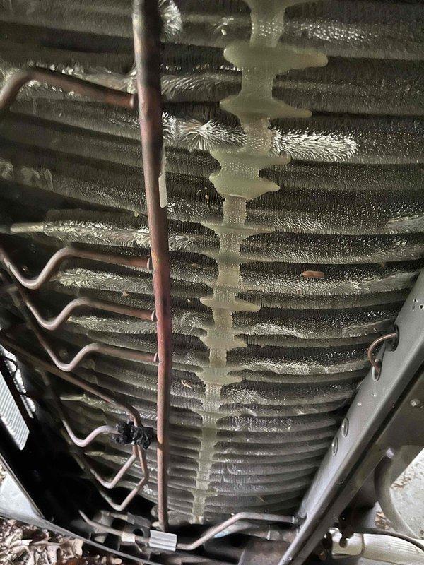 Completed BFMA tune-up service on a 5-year-old residential air conditioning system. Upon inspection, discovered significant ice and frost buildup on the evaporator coil assembly, indicating a potential refrigerant restriction, airflow issue, or low refrigerant charge. Documented the iced coil condition and outdoor condensing unit with photographs. The heavy frost accumulation on the upper portions of the coil fins and copper refrigerant lines suggests the system was experiencing reduced cooling capacity and efficiency. Inspected the outdoor condensing unit, which appeared in serviceable condition with proper installation on a concrete pad. The unit showed normal wear consistent with its age, with some debris accumulation noted. Recommended further diagnostic testing to determine the root cause of the freezing condition, which may require checking refrigerant levels, verifying proper airflow across the coil, inspecting the metering device, and evaluating the air filter and ductwork for 