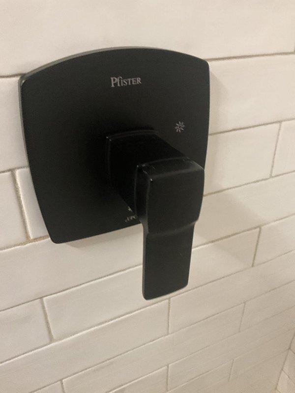 Completed installation of Pfister shower valve system and tub spout in residential bathroom. Mounted matte black single-handle shower control valve with trim kit on white subway tile wall, ensuring proper alignment and secure attachment. Installed matching black tub spout at appropriate height above tub deck. Verified water flow, tested temperature control operation, and confirmed no leaks at all connection points.