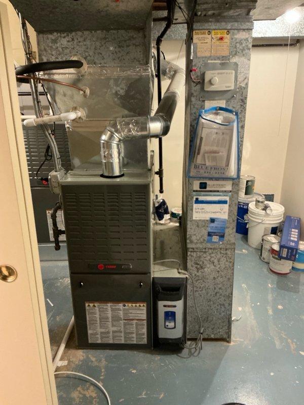Completed full HVAC system installation in basement utility area, replacing existing equipment with Trane 6/16 SL280 two-stage variable speed furnace and EL15 single-stage air conditioner, upgraded to 16 SEER efficiency rating. Installed all necessary ductwork connections with metallic silver transitions and elbow joints from furnace unit. Connected electrical wiring and mounted control components on concrete block wall. Applied Lennox instant rebate program and included complimentary water heater installation as part of system upgrade package. Verified all mechanical connections, tested system operation for proper heating and cooling cycles, and confirmed variable speed blower motor functionality. All equipment installed to manufacturer specifications with proper clearances maintained around furnace unit and associated components.
