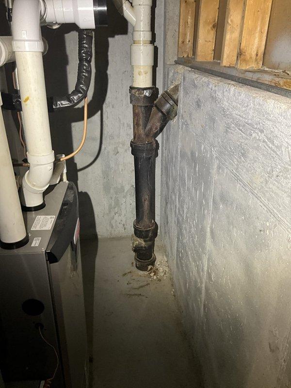 Performed comprehensive inspection of tanked water heater system exhibiting visible corrosion and aging on galvanized steel piping connections. Assessed condition of plumbing infrastructure including multiple threaded pipe joints, valve assemblies, and water heater tank insulation. Documented extensive rust formation on metal surfaces, corroded cast iron drainage piping, and deteriorating pipe fittings throughout the installation. Evaluated water heater for potential replacement due to advanced age indicators including compromised insulation jacket and oxidized connection points.