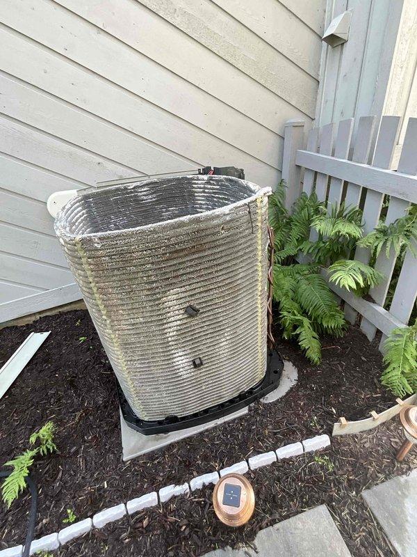 Completed comprehensive BFMA tune-up on an 11+ year old cylindrical air conditioning condenser unit. Performed standard maintenance protocol including inspection of metal fins showing oxidation and weathering, verification of refrigerant line connections, assessment of concrete pad and drain pan condition, and evaluation of overall system operation. Unit serviced during afternoon appointment as requested, with documentation photos captured showing equipment condition and surrounding installation area.