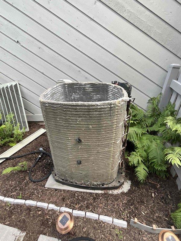 Completed comprehensive BFMA tune-up on an 11+ year old cylindrical air conditioning condenser unit. Performed standard maintenance protocol including inspection of metal fins showing oxidation and weathering, verification of refrigerant line connections, assessment of concrete pad and drain pan condition, and evaluation of overall system operation. Unit serviced during afternoon appointment as requested, with documentation photos captured showing equipment condition and surrounding installation area.
