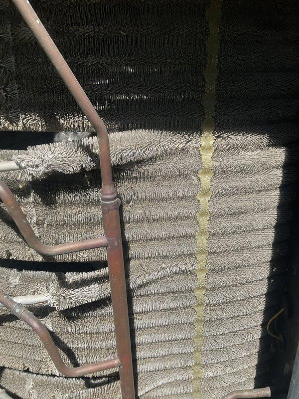 Completed comprehensive BFMA tune-up service on residential air conditioning system with equipment age exceeding six years. Performed standard maintenance protocol including system inspection, evaporator coil assessment, and refrigerant line examination. Visual inspection revealed significant dust and debris accumulation on evaporator coil assembly, with coils displaying contrasting conditions between upper and lower sections. Documented copper refrigerant lines showing surface discoloration consistent with age and outdoor exposure. System components photographed for service records, showing spiral-configured evaporator coil with multiple concentric rings and parallel fin arrangement housed within outdoor cabinet. All tune-up procedures performed according to BFMA standards with system operational upon completion.