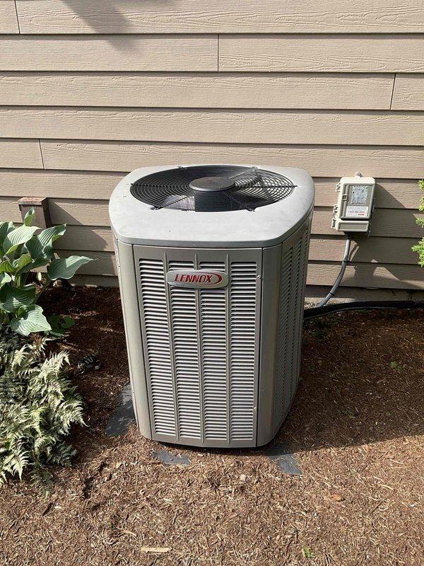 Completed comprehensive BFMA tune-up service on residential Lennox outdoor air conditioning condenser unit. Performed standard maintenance protocol including visual inspection of unit components, verified proper airflow through mesh panels, checked fan operation and grille assembly, and inspected electrical disconnect box mounted on exterior wall. Unit found in operational condition with normal weathering and dirt accumulation on protective mesh panels consistent with outdoor exposure; all components functioning within normal parameters.