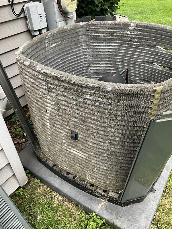 Completed comprehensive BFMA tune-up service on residential air conditioning system aged 9+ years. Outdoor condenser unit exhibited heavy accumulation of lint, dust, and debris throughout coil surfaces, significantly restricting airflow and reducing system efficiency. Performed thorough cleaning of condenser coils, removing dense matted buildup from fins and cylindrical coil structure. Inspected internal components including compressor, fan motor assembly, electrical connections, and capacitor. Verified proper operation of all electrical wiring and connections. System restored to optimal operating condition with improved airflow and heat transfer capability.