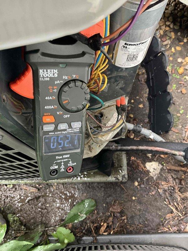 Completed comprehensive BFMA tune-up service on 10-year-old air conditioning system during scheduled morning appointment. Performed electrical diagnostics using digital multimeter to verify capacitor functionality and measure operating voltages, with readings indicating proper system performance at 52.1 volts. Inspected condenser coil fins which showed moderate accumulation of dust, dirt, and debris requiring attention to maintain optimal heat transfer efficiency and system performance.