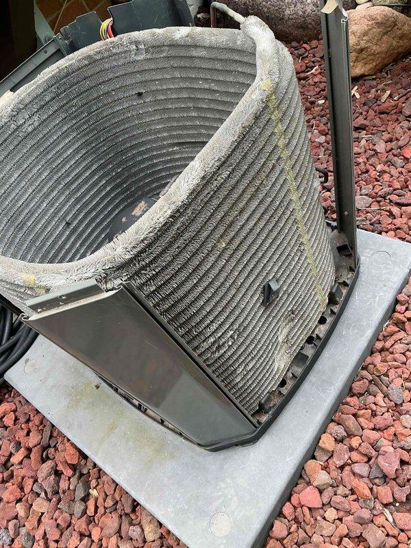 Completed comprehensive air conditioning tune-up on a 6-year-old outdoor condensing unit. Removed top panel to access condenser coil, which exhibited significant accumulation of dirt, dust, debris, and organic growth with yellowish-green discoloration throughout the fin surfaces. Thoroughly cleaned condenser coil to remove buildup and restore proper airflow and heat transfer efficiency. Performed standard maintenance inspection of all accessible components, reassembled unit, and verified proper operation upon completion.