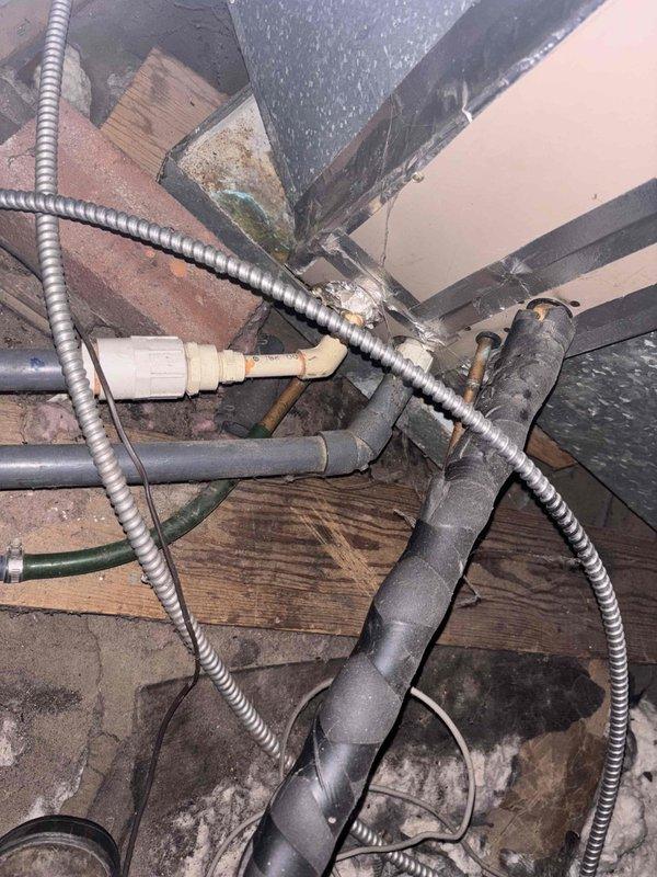 Responded to service call for air conditioning system blowing warm air in older home with unit components located in attic crawl space. Accessed confined attic area to inspect HVAC equipment, ductwork, and associated refrigerant lines. Evaluated system components including condensate drainage, electrical conduits, and mechanical connections at junction points where multiple utility lines intersect with structural framing. Documented existing conditions of aged equipment and infrastructure routing through unconditioned space for service records.