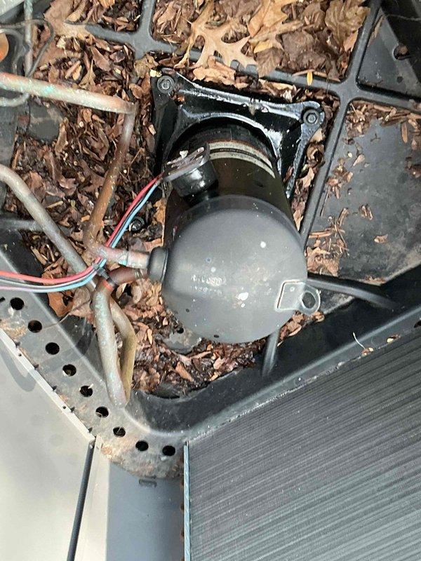 Completed comprehensive BFMA tune-up service on air handler system. Upon arrival, found outdoor condensing unit with significant debris accumulation including dried leaves and organic matter surrounding motor assembly and within equipment housing. Performed thorough cleaning of condenser unit, removing all debris from housing pan and around compressor motor. Inspected all electrical connections including motor wiring harness with red, white, and blue conductors. Evaluated heat exchanger coil fins and copper refrigerant lines for proper condition. Checked all brass fittings, valve connections, and refrigerant line connections at evaporator coil assembly. Verified system components operational and cleared all obstructions to ensure proper airflow and equipment function.