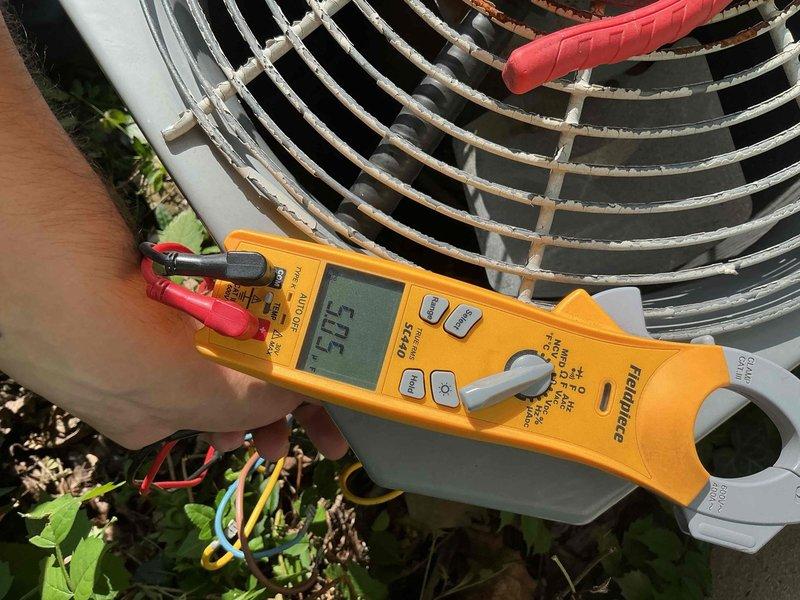 Completed comprehensive BFMA AC tune-up on 24-year-old system, including electrical testing of outdoor condenser unit with readings indicating proper voltage levels at 50.5V, and inspection of indoor air handler with verification of clean pleated air filter in proper position within housing. All components found operating within normal parameters with no immediate service concerns identified during preventative maintenance visit.