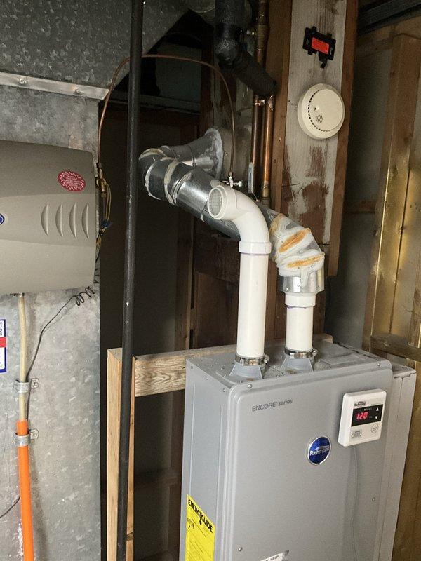 Completed comprehensive tune-up and maintenance on Encore series tankless water heater system addressing reported low water pressure concerns. Performed standard BFPMA protocol including system inspection, flushing procedures, filter cleaning, and verification of all inlet/outlet connections and PVC venting components. Confirmed unit operating at proper temperature setpoint of 120°F with digital display functioning correctly, all piping connections secure, and water flow restored to normal pressure levels.