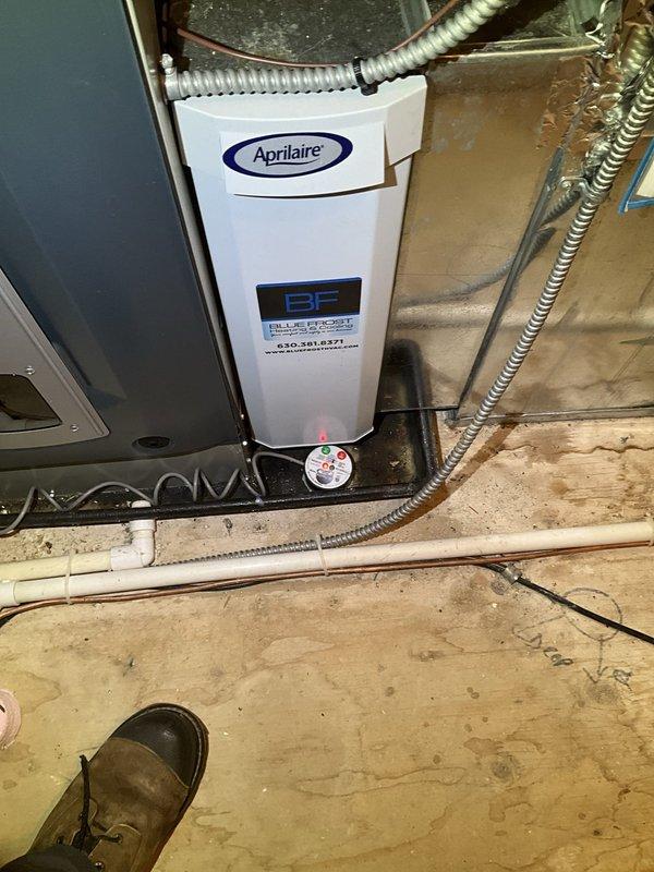 Responded to no cooling complaint for upstairs unit located in attic/crawlspace. Upon arrival, performed diagnostic inspection of HVAC system including condensate drain assembly, ductwork, and air handler components. Inspected Aprilaire equipment, verified electrical connections, and examined flexible ductwork for proper airflow. System components photographed for documentation purposes, showing condensate piping configuration, air handler installation, and associated mechanical equipment in operational condition.