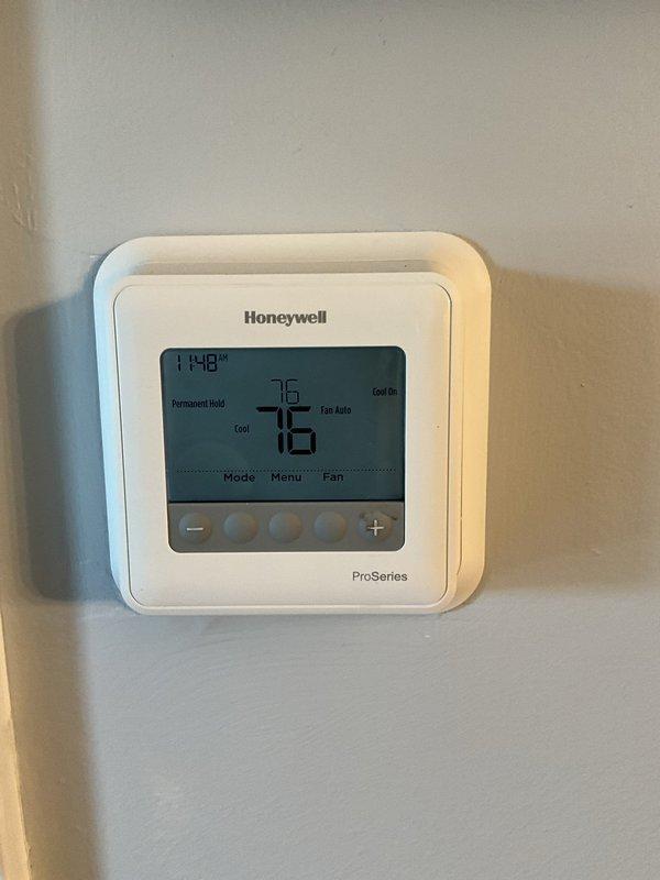 Completed comprehensive BFMA tune-up on 9+ year old air conditioning system located in utility closet on balcony. Performed full inspection of blower motor assembly, electrical components, circuit board, relays, and all wiring connections within the unit cabinet. Verified Honeywell ProSeries thermostat operation showing system in cooling mode with fan set to auto at 76 degrees with permanent hold setting active.