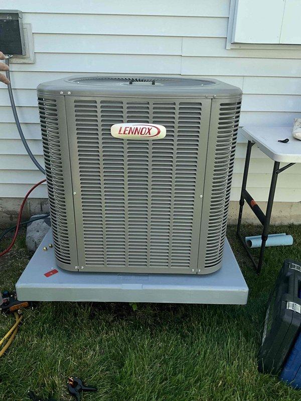 Completed installation of Lennox ML13KC1 air conditioning unit with matching cased evaporator coil in residential utility closet. Connected refrigerant lines, condensate drainage system via PVC piping, and electrical components including outdoor disconnect box. Reinstalled thermostat and verified system operation with existing Lennox furnace for proper heating and cooling integration.