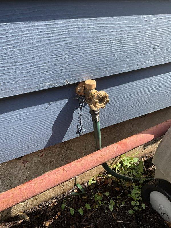 Shut off main water supply to residence and drained entire plumbing system. Cut and removed approximately 12"x18" section of drywall in basement bedroom wall to access existing hose bib location. Removed old hose bib and installed new frost-free hose bib with copper pipe, fittings, and appropriate sealants. Added 1/2" isolation valve for future maintenance access. Work includes one-year warranty on installation. Drywall repair and installation of access panel for isolation valve to be completed by others.