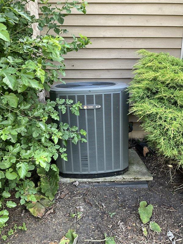 Completed comprehensive BFMA tune-up service on a 10-year-old outdoor air conditioning unit. Performed full system inspection including condenser coil examination, refrigerant line assessment, and verification of unit operation. Observed frost accumulation on evaporator coil fins indicating potential airflow restriction or refrigerant charge concerns; documented copper refrigerant tubing showing normal oxidation consistent with outdoor exposure. Verified unit is positioned on stable concrete pad with adequate clearance from surrounding landscaping including vine growth and evergreen shrubs. All maintenance procedures completed per BFMA standards with system operational at time of departure.