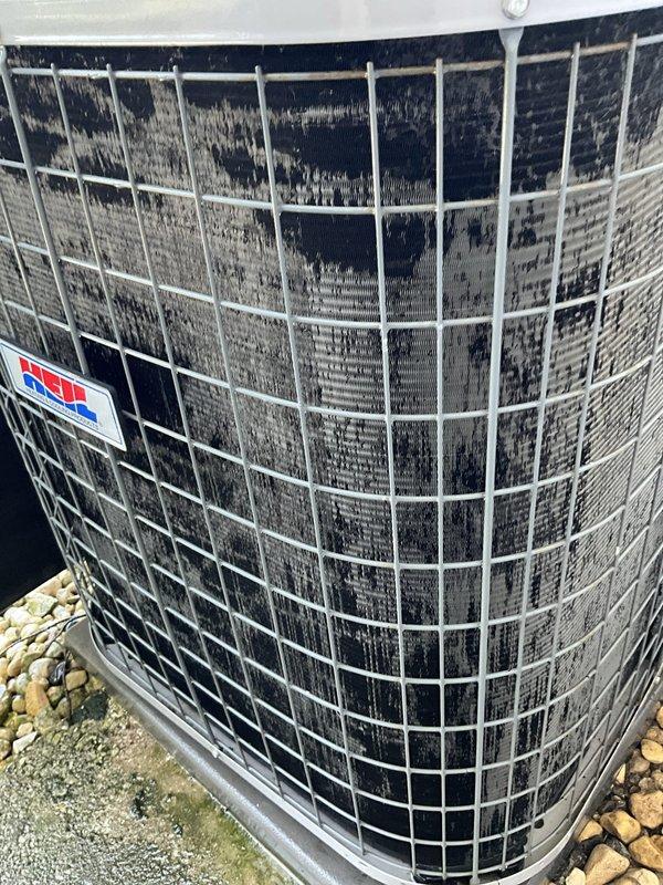 Completed comprehensive BFMA tune-up on 14-year-old Heil air conditioning condenser unit located in side yard enclosure. Performed standard preventative maintenance protocol including system inspection, cleaning of heavily soiled condenser coils which exhibited significant accumulation of dirt, dust, and debris throughout the fin surfaces, and verification of proper operation. Unit was found to be operational with protective wire mesh cage intact and equipment properly positioned on concrete pad with adequate ventilation clearances maintained within privacy fence enclosure.