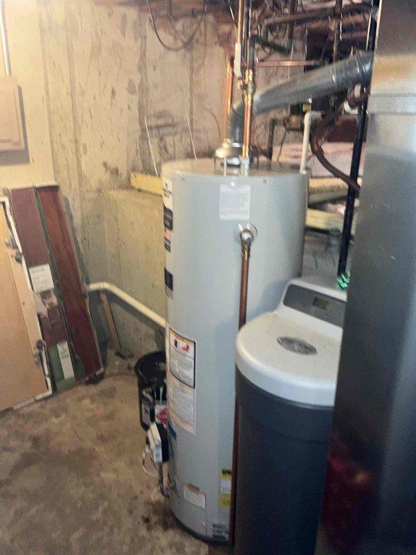 Completed residential water heater installation in basement utility area as part of full system package. Installed new standard capacity tanked water heater with proper copper piping connections, ensuring all supply and discharge lines were securely fitted and code-compliant. Integrated unit with existing plumbing infrastructure including water softener system, verified all connections for proper operation and tested system functionality upon completion.