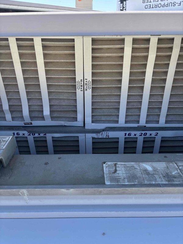 Completed quarterly BFMA filter change service on rooftop unit at commercial facility. Accessed RTU and replaced two 16x20x2 pleated air filters in the air handler section. Upon arrival, mall office was closed, so coordinated access through security personnel. Both filters were successfully installed in the metal filter rack housing, documented with photos showing proper fit and installation date marking. Unit operational following filter replacement, maintaining scheduled preventative maintenance protocol for optimal air quality and system efficiency.