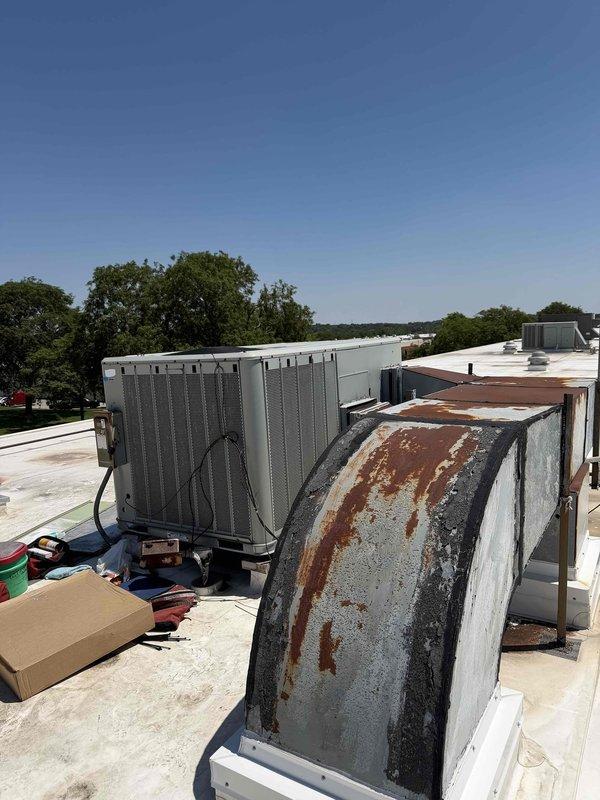 Performed commercial RTU repair with parts and refrigerant staged from headquarters. Replaced heavily corroded and rusted exterior panel showing extensive weathering damage with vertical streaking patterns. Connected manifold gauge set to system and performed refrigerant charging procedures using Yellow Jacket diagnostic equipment, monitoring pressures on both high and low side gauges to verify proper system operation and refrigerant levels.