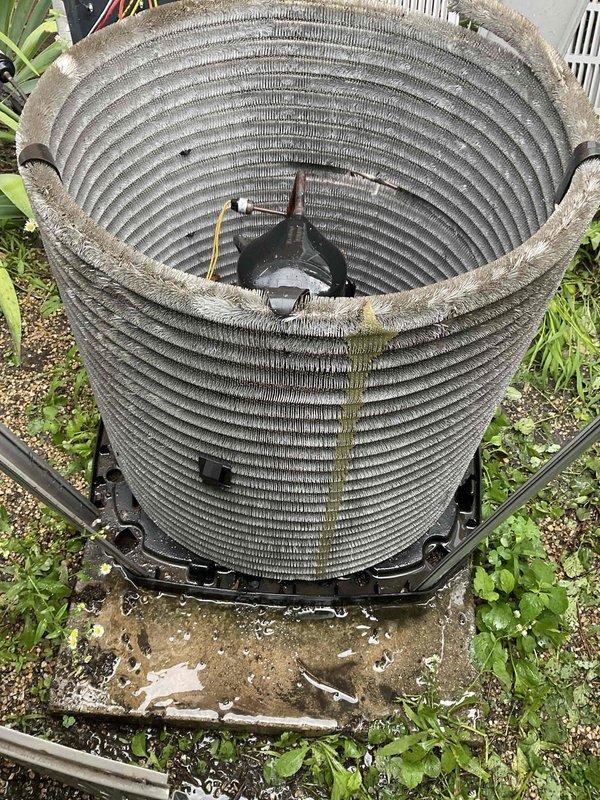Completed comprehensive BFMA tune-up on outdoor air conditioning condenser unit aged 6+ years. Removed protective cover to access cylindrical condenser coil assembly, which exhibited heavy accumulation of dirt, debris, dust, and organic matter including moss and algae growth along the upper rim and throughout the fin surfaces. Performed thorough cleaning of condenser coils to restore proper airflow and heat transfer efficiency, addressing significant buildup that had accumulated from extended outdoor service exposure. Inspected electrical components, wiring, and internal connections for proper operation. Reassembled unit and verified system performance upon completion of maintenance service.